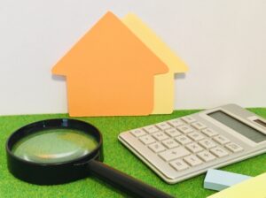 家の模型と虫眼鏡と電卓