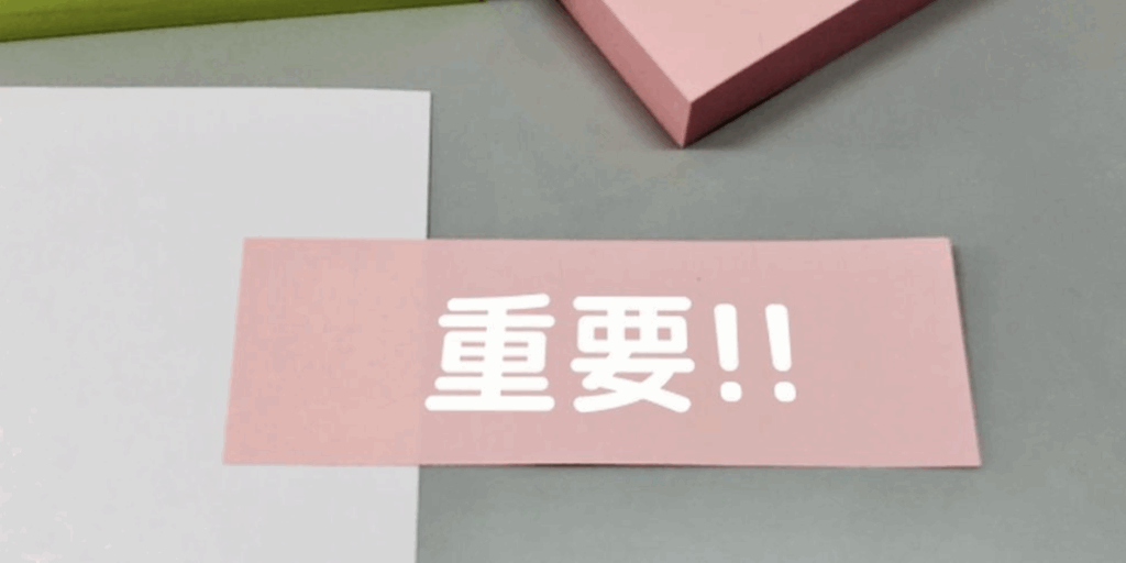 『重要!!』と書かれたピンクの付箋と文具、注意を促すイメージ