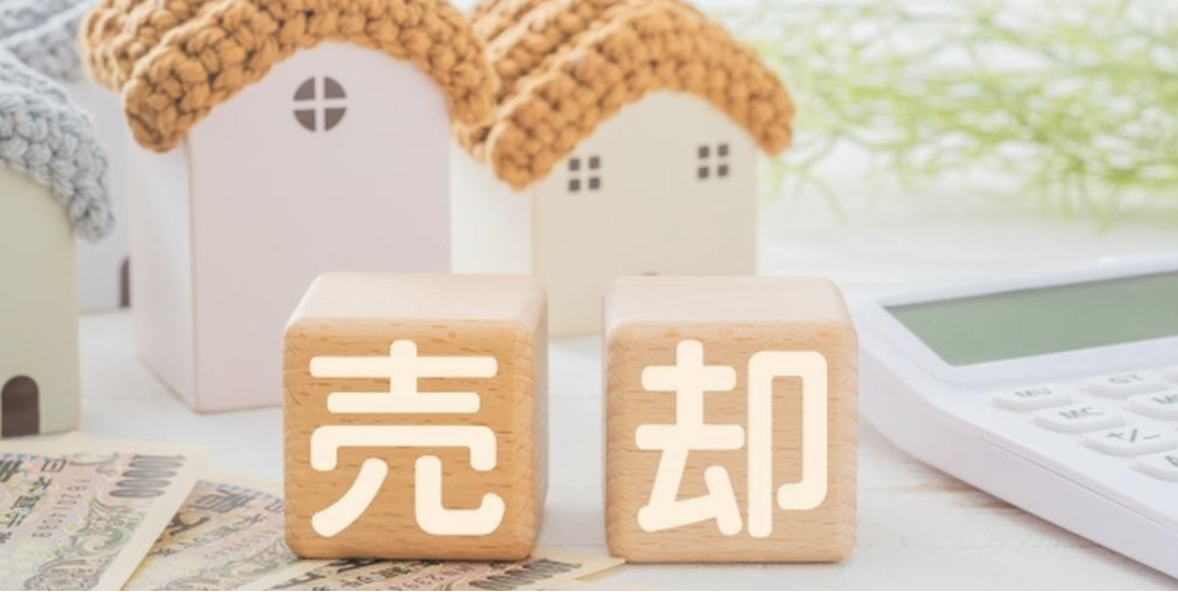 「売却」の文字と家の模型、電卓、紙幣が並ぶイメージ